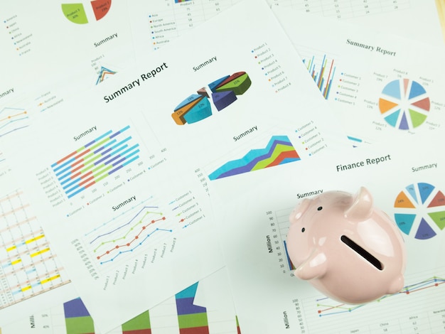 Фото Диаграмма бизнес-отчета и анализ финансового графика с розовый копилка на столе.