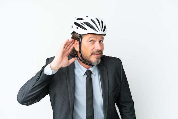 흰색 배경에 격리된 자전거 헬멧을 쓴 사업가가 귀에 손을 대고 무언가를 듣고 있다