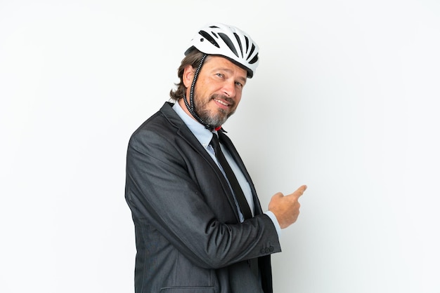 Business senior man with a bike helmet isolated on white background pointing back