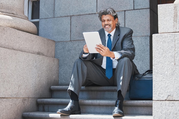 Business stairs and man outdoor with a tablet smile and connection with social media relax and communication Male person employee and consultant with technology mobile app and online reading