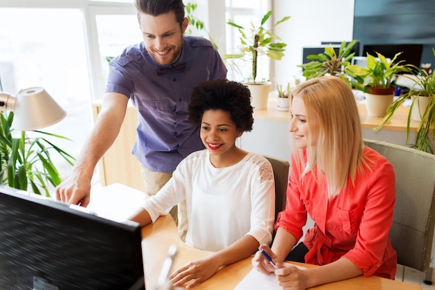 Foto business, startup en people concept - gelukkig creatief teamnetwerk met computer op kantoor