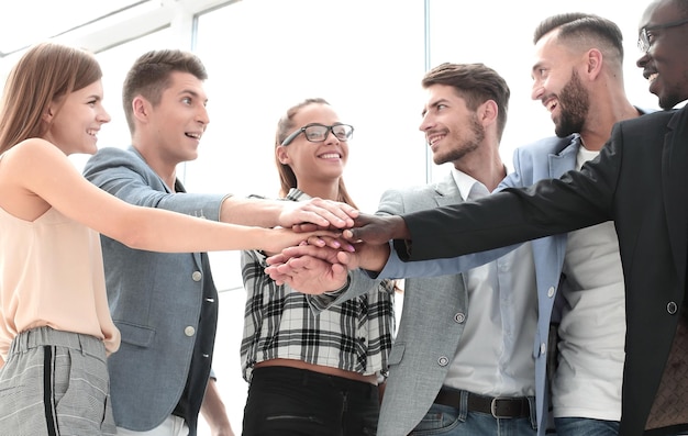 起業のジェスチャーの人々とチームワークの概念は、オフィスでお互いの手を重ねて幸せな創造的なチーム