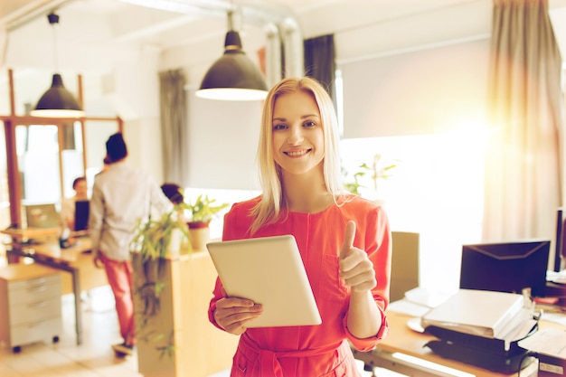 business, startup and people concept - happy businesswoman or creative female office worker with tablet pc computer showing thumbs up