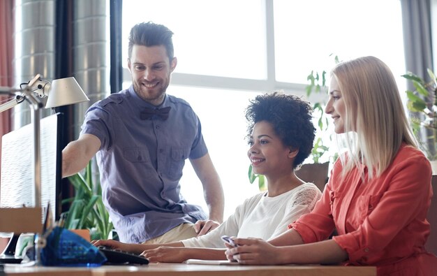 Photo business, startup and people concept - happy creative team networking with computer in office