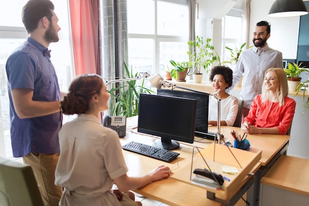 business, startup and people concept - happy creative team talking in office