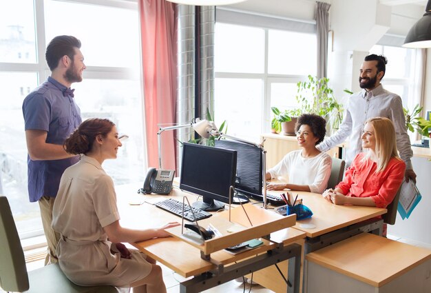 business, startup and people concept - happy creative team talking in office