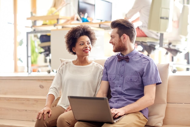 business, startup and people concept - happy creative team with laptop computer in office