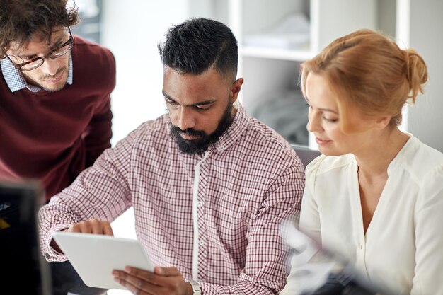 business, startup and people concept - international creative team with tablet pc computer in office