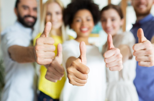 Photo business, startup, people, gesture and teamwork concept - close up of happy smiling creative team showing thumbs up in office