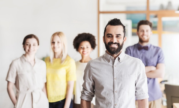 business, startup, people and teamwork concept - happy young man with beard over creative team in office