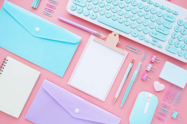 Business and stationery accessories neatly laid out on a pink background. Flat layout, top view.
