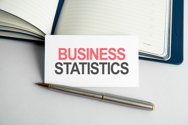 Business statistics. text business report life writing on paper card, notebook on wooden background