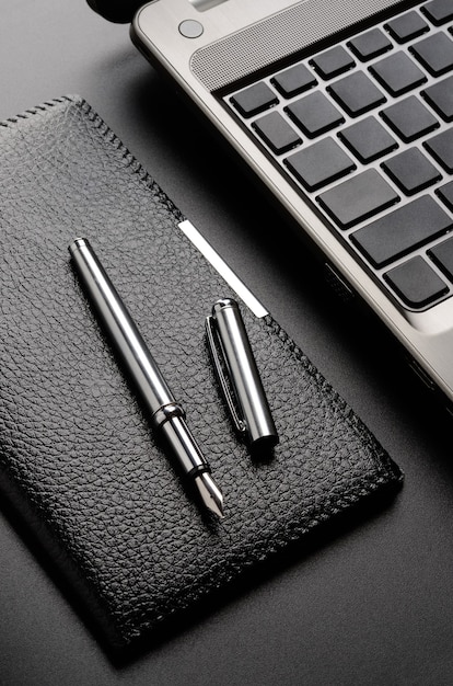 Business still life: laptop, card holder, fountain pen.