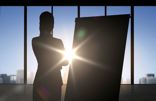 business, strategy, planning and people concept - silhouette of woman with flipboard over office window background and sunlight