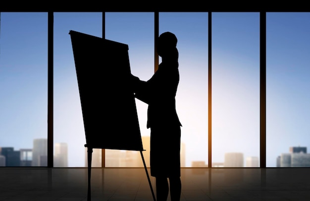 business, strategy, planning and people concept - silhouette of woman with flipboard over office window background