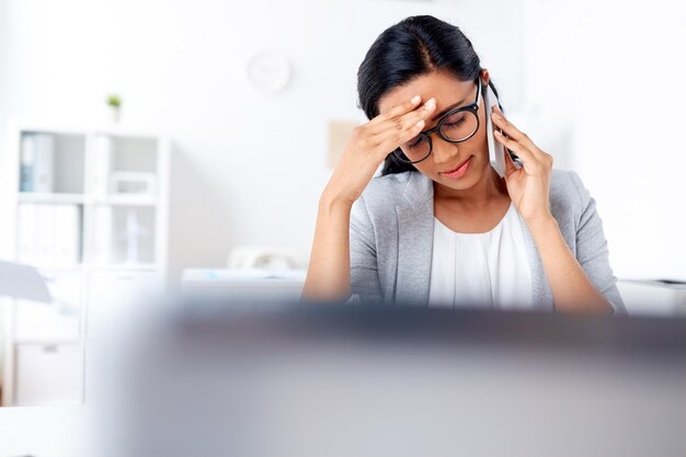 business, stress and people concept - businesswoman calling on smartphone at office