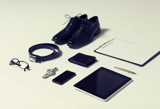 Business, style, clothes and objects concept - close up of formal male clothes and personal stuff on table at home