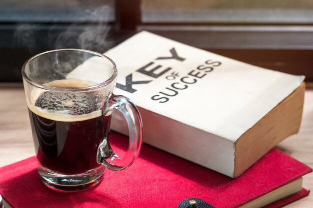 Business of success book and black coffee on wood near window in light morning