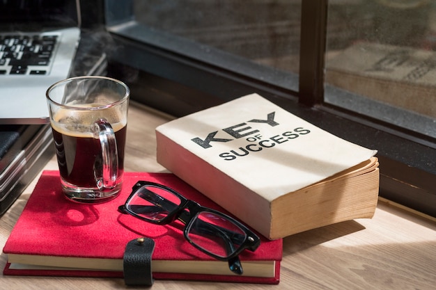 Business of success book, glasses, laptop and black coffee.