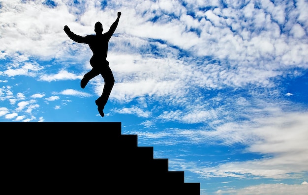 Business success concept. Silhouette of a happy businessman jumping on the stairs