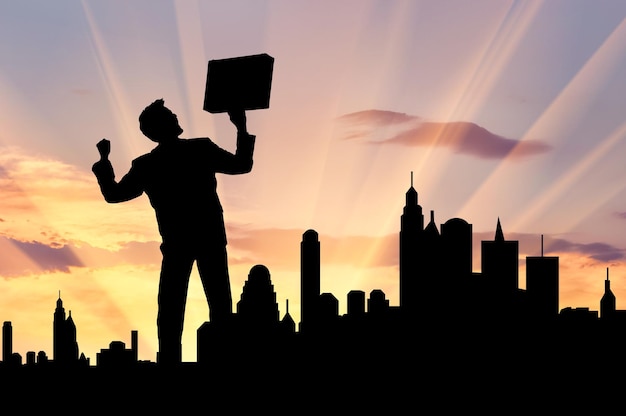 Business success concept. Silhouette of a happy businessman with a briefcase in his hands against the evening city