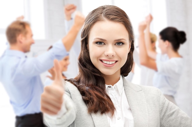 business and success - happy businesswoman showing thumbs up in office