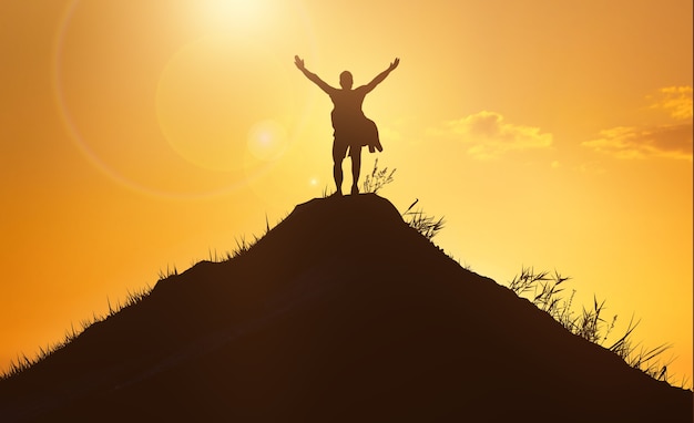 Concetto di affari e successo, leadership e successo. siluetta dell'uomo sulla cima della montagna sopra il fondo del cielo al tramonto. alzi la foto