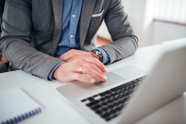 Business success and technology concept. Businessman in formal wear working on laptop, close-up.