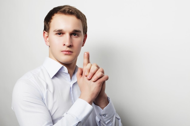 Business successful and people concept Handsome young business man in white shirt looking at camera standing against grey background