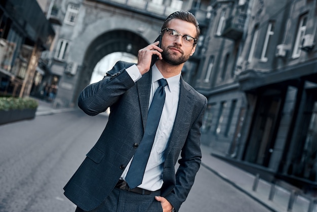 Business talk handsome young man in full suit talking on the phone cropped view