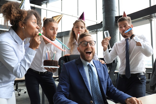 Foto squadra di affari che celebra un compleanno di collega nell'ufficio moderno.
