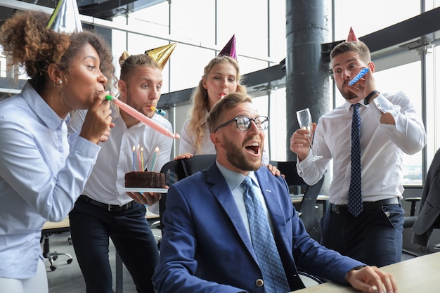 Foto squadra di affari che celebra un compleanno di collega nell'ufficio moderno.