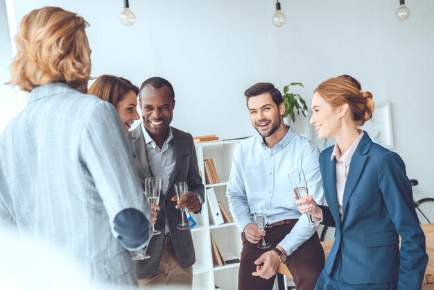 Photo business team celebrating with beverage in glasses at office space