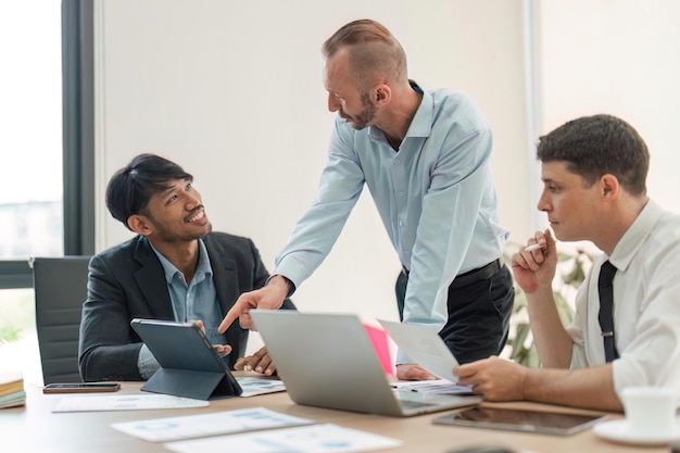 Business team discussing online project showing computer presentation to skilled team leader Friendly diverse colleagues working in pairs on laptop