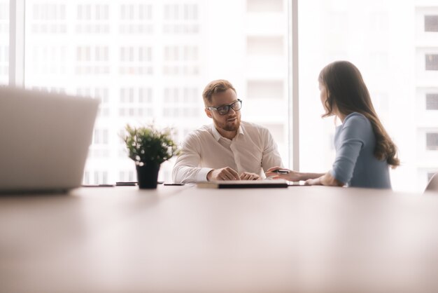 Business team discussing project in light office room sitting next to a window