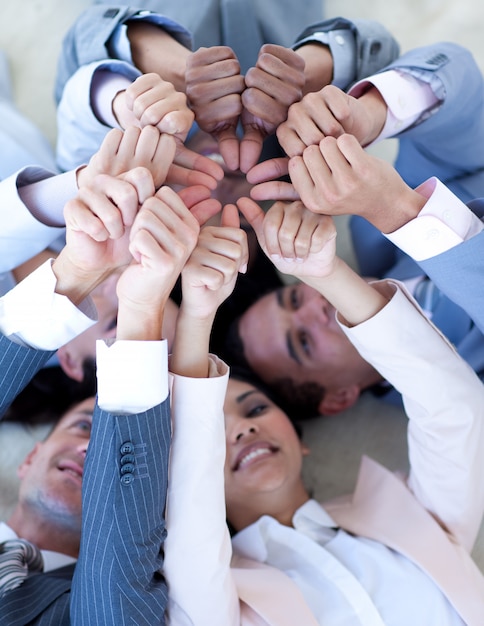 Business team on floor in a circle with thumbs up