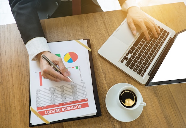 Business team hands at work with financial reports and a laptop