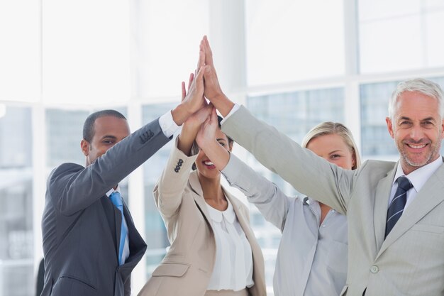 Business team high fiving and smiling at camera