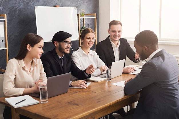 Business team in gesprek met Afro-Amerikaanse aanvrager. Jonge kandidaat op werkgesprek in modern kantoor, kopieer ruimte