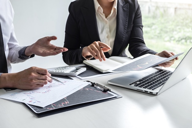 Foto investitore del team aziendale durante l'incontro con la pianificazione e l'analisi della cooperazione tra partner nel progetto di marketing di trading di investimenti e puntando sui dati presentati e trattando una borsa per trarre profitto.