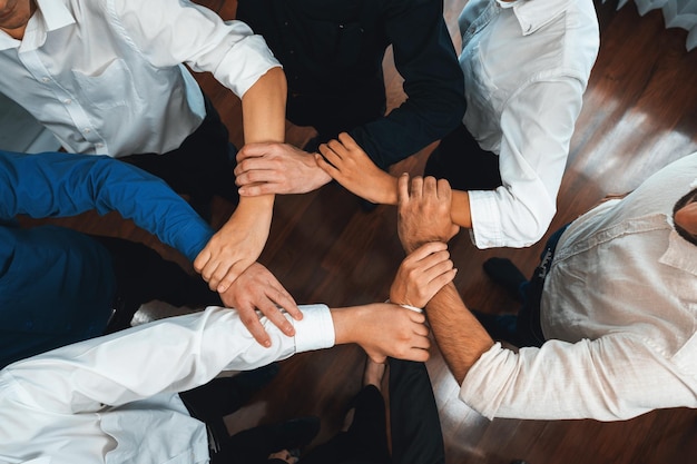 ビジネスチームが一緒に円形に手を取り合うことは、ビジネスパートナーシップの成功グループと地域の職場における強力な集団的団結のチームワークを象徴しています