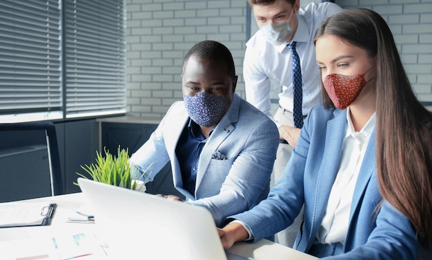 Business team met beschermende maskers werkt op kantoor.