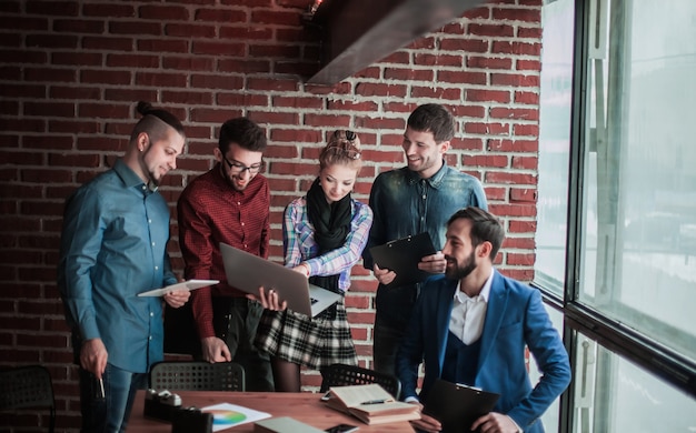 Business team met laptop en documenten over een nieuw project in de buurt van de werkplek in moderne kantoren