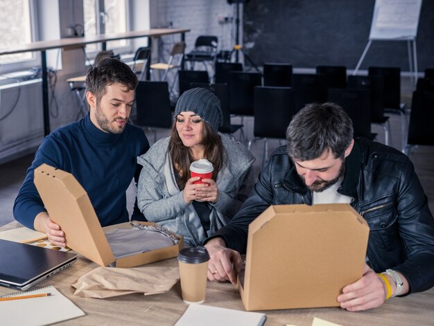 Business team opening pizza and drinking in office