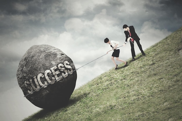 Photo business team pull a boulder with success text