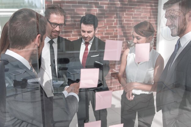 Business team reads business notes on a glass Board