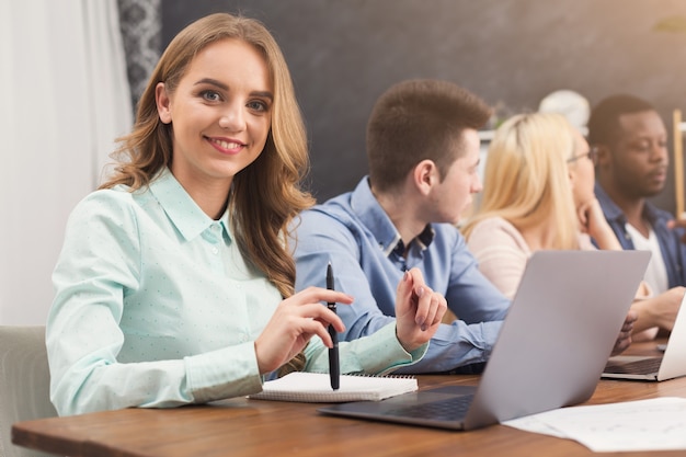 Gruppo di affari che parla dei risultati del loro lavoro. gruppo di uomini d'affari allegri che discutono di una nuova strategia di marketing, giovane donna che sorride alla telecamera, copia spazio