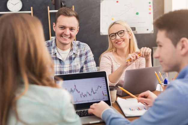 Foto gruppo di affari che parla dei risultati del loro lavoro. gruppo di uomini d'affari allegri che studiano il grafico sul laptop, discutono di una nuova strategia di marketing, siedono in ufficio, copiano lo spazio