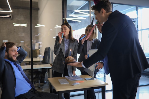 Business team viert een verjaardag van een collega in het moderne kantoor.