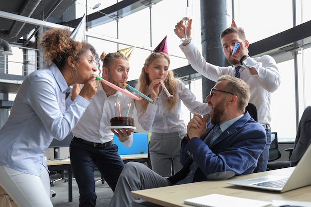 Foto business team viert een verjaardag van een collega in het moderne kantoor.